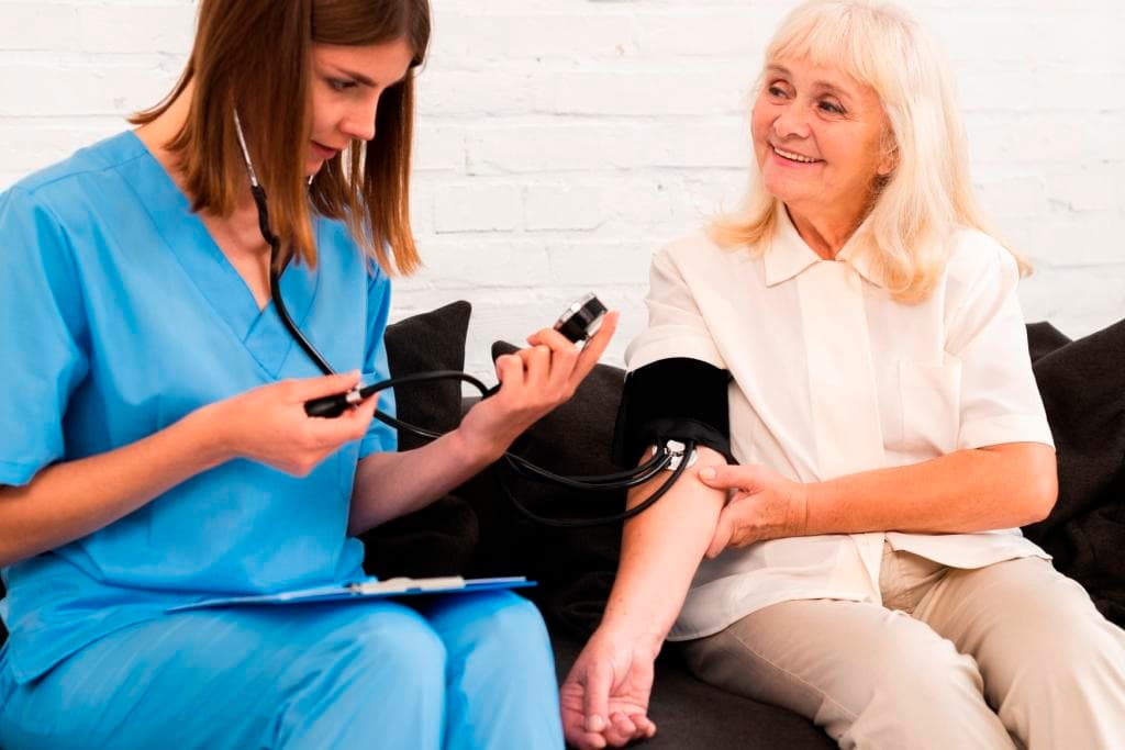 Caregiver assisting with blood pressure and diabetes monitoring at home in NYC